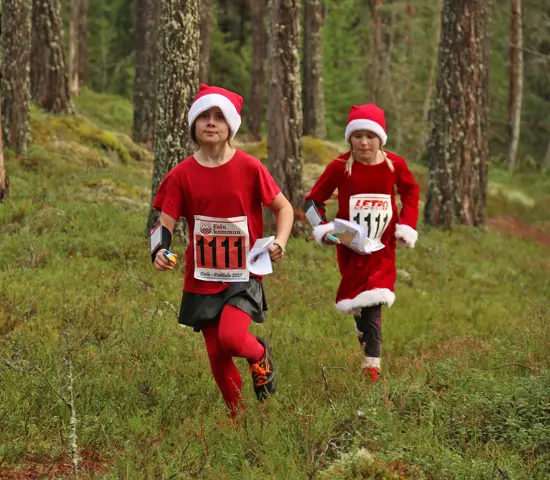 Två "tomtar" springer genom skogen på Daladubbeln 2025.